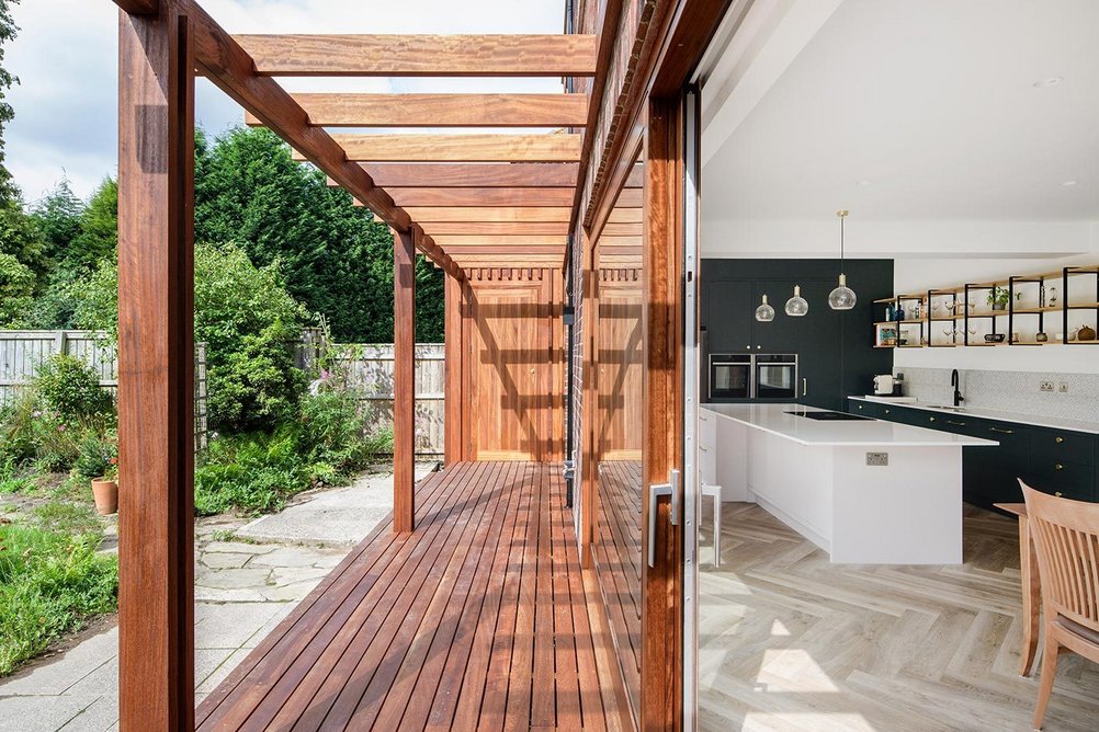 ) The new loggia makes a deep threshold between the kitchen-diner and the garden.