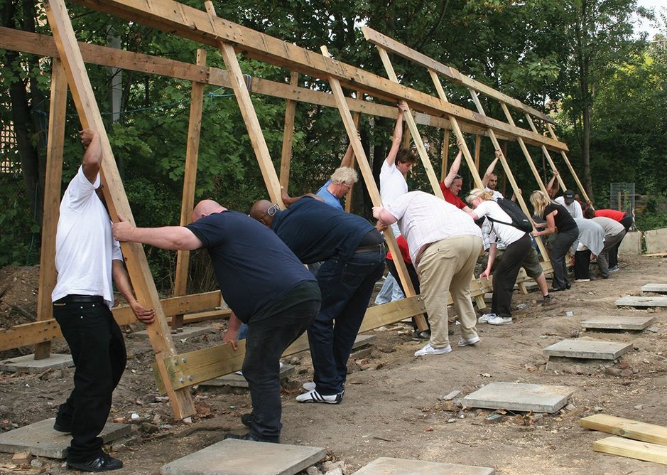 A squad of volunteers helps to reassemble the reborn building on its minimal foundation pads.