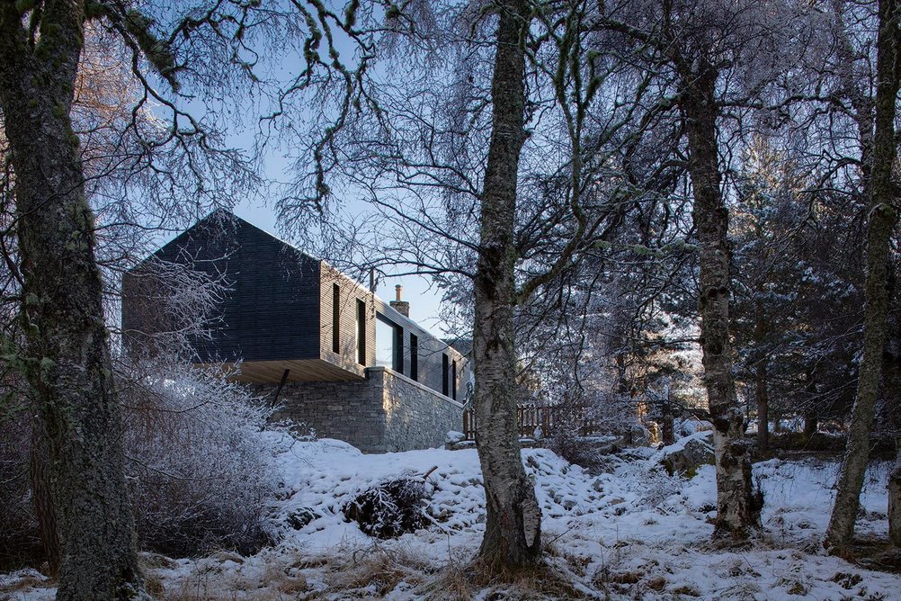 The new extension continues the ground floor of the original farmhouse over the sloping side onto a new plinth that ends with a cantilever.