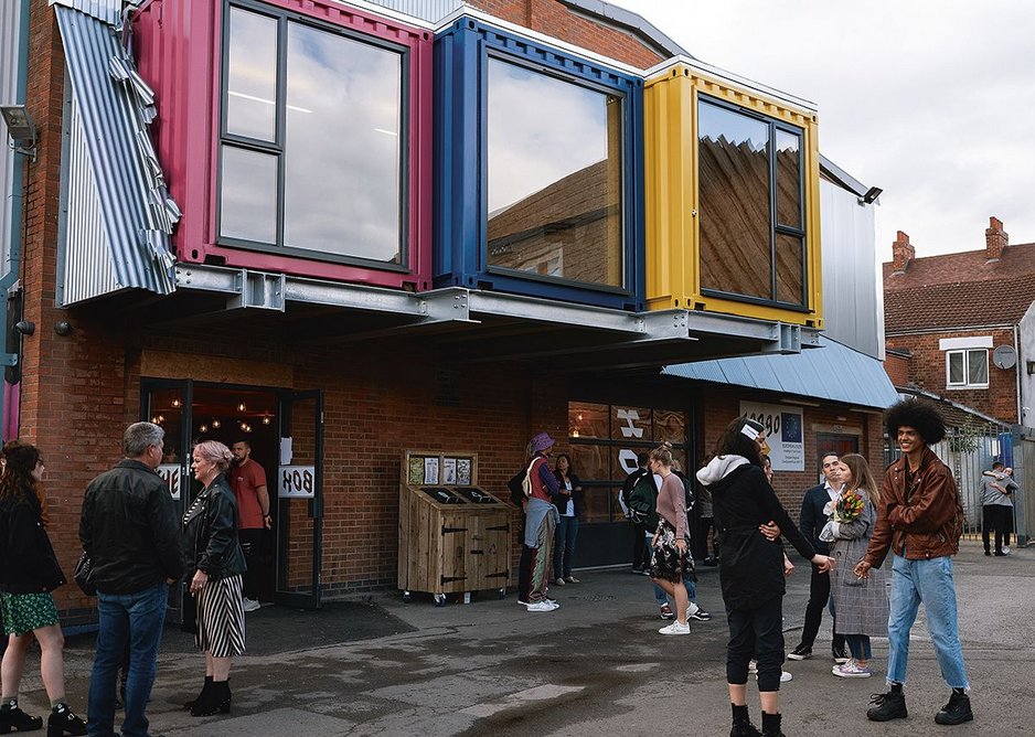 Shipping containers punched through the facade enliven the street.