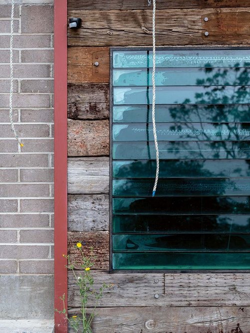 Salvaged railway sleepers and panes of glass are recomposed in the facade.