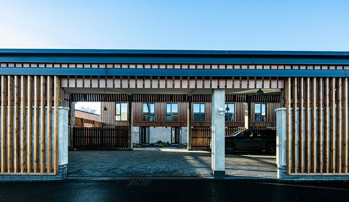 View through the car parking barn to the row of houses, designed by Peak Architects.