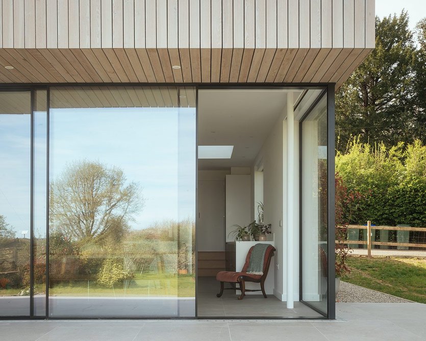 Timber cladding wraps around the overhand, making a crisp junction with the sliding doors.