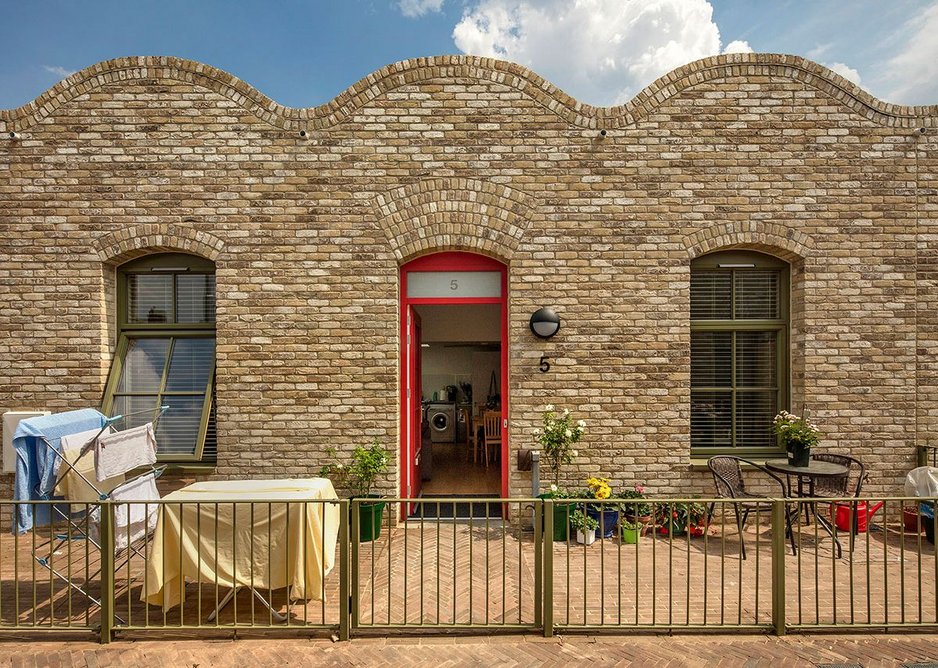 Homes have individually coloured front doors, and the wavy roofline echoes vaulted ceilings inside.