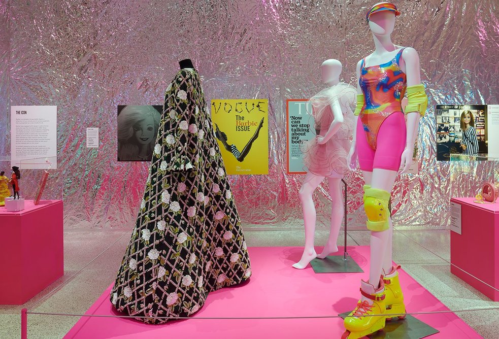 Installation showing a gown designed by Oscar de la Renta and a roller blading outfit from Barbie the movie at Barbie®: The Exhibition at the Design Museum.