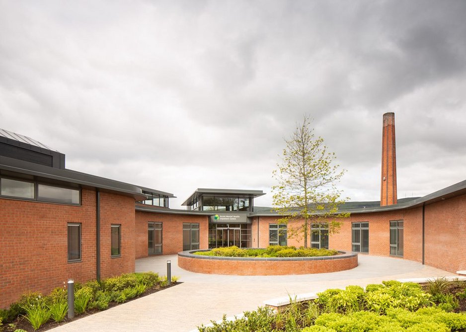 The point of arrival is the first of a sequence of landscaped courts. Chimney of existing building to the rear.