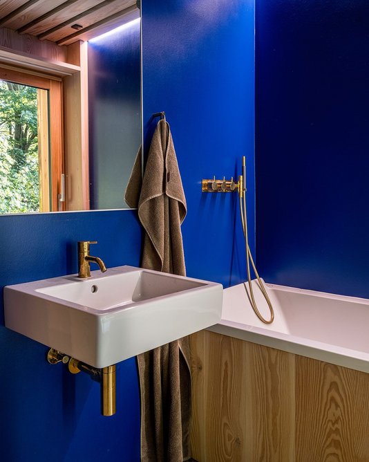 The Yves Klein blue continues in the bathroom, over the walls with tadelakt-style plaster and complementary gold faucets.