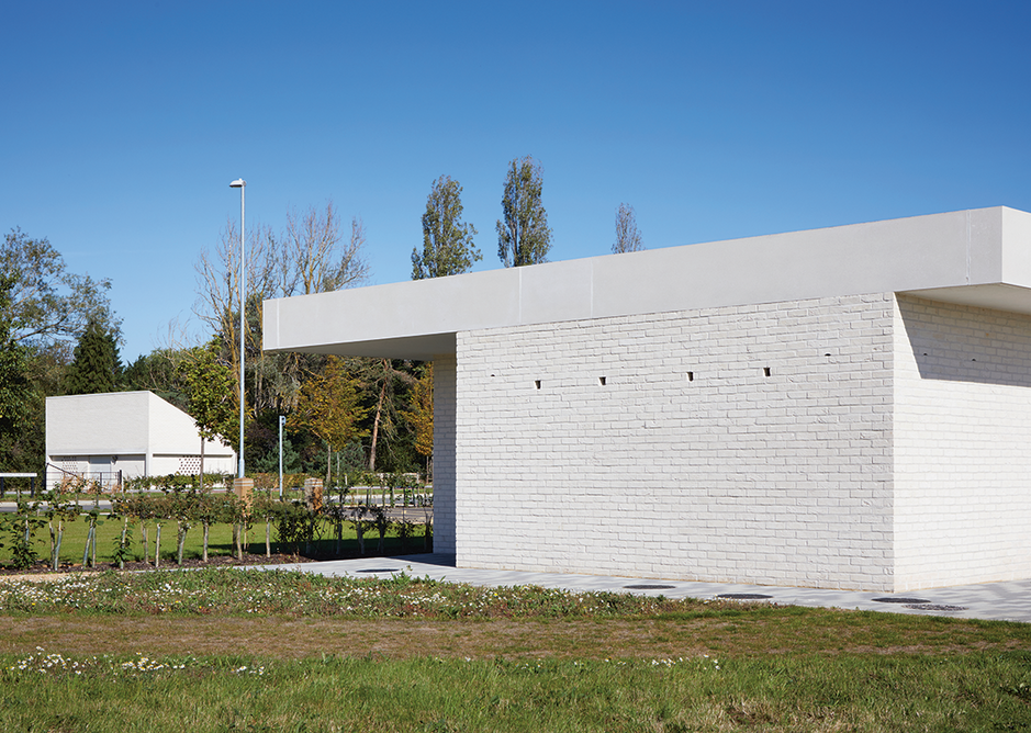 The short elevation of the sports pavilion with the electrical substation beyond. Homes for birds and bats have been created in the cavity walls, accessed via two types of hole in the facade.