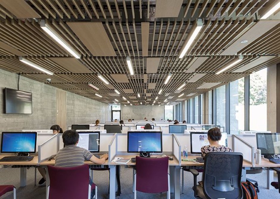 In the library extension's post-graduate study space, the necessary mechanical ventilation kit is masked in line with the attenuating oak slat detailing elsewhere.