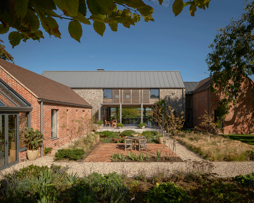 Harbour House in West Sussex has red brick volumes that flank the central knapped flint main part of the house. Views carry through from one elevation to the other to connect the garden to the harbour on the northern side.