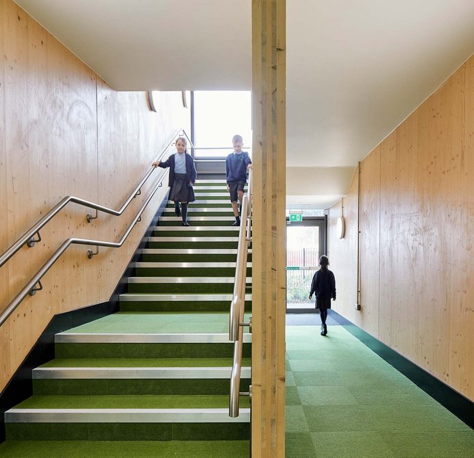 The school’s exposed CLT structure creates a warm and friendly aesthetic. Green flooring adds to the link with the outdoors.