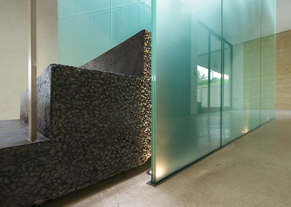 There’s some bold detailing evident internally with a central staircase of black concrete and frosted green glass.