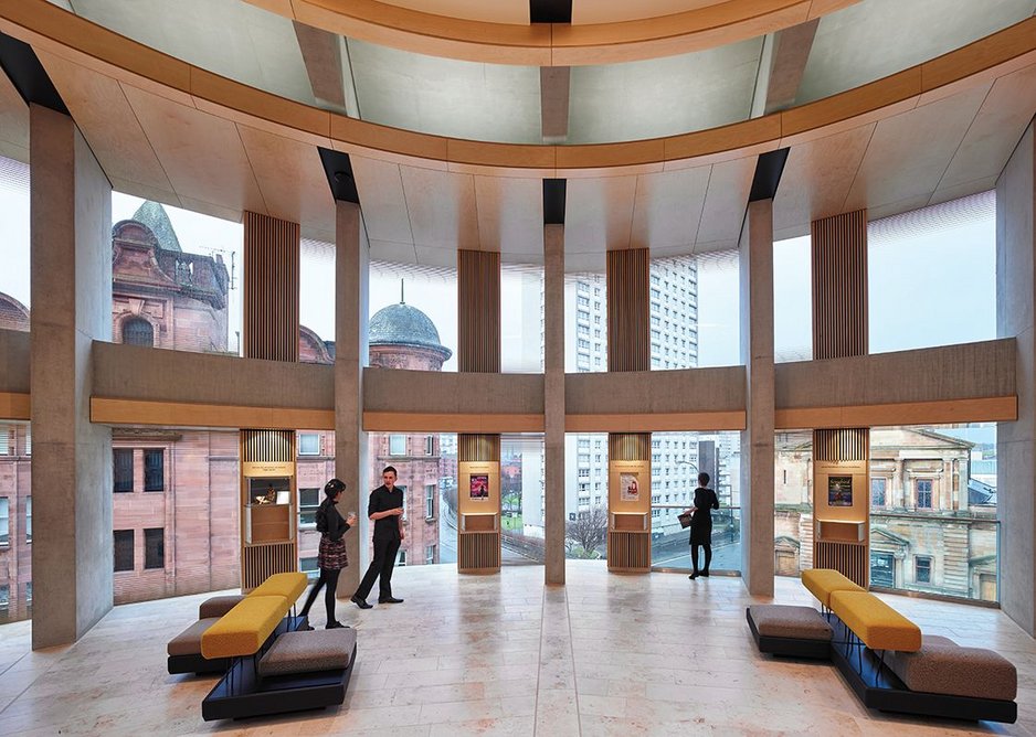 Timber-clad ventilation ducts sit between concrete piers in the multi-level foyer space.