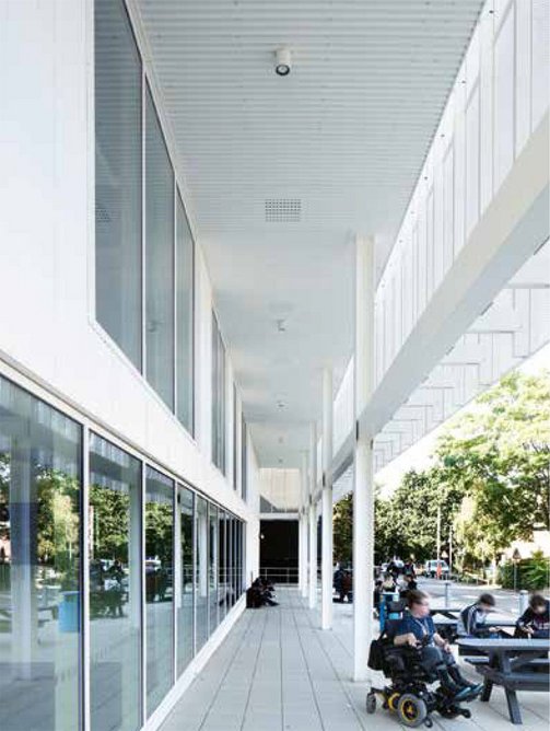 With the cladding line recessed deeply behind the aluminium mesh outer skin, a narrow covered arcade complements the covered plaza on the main entrance side.