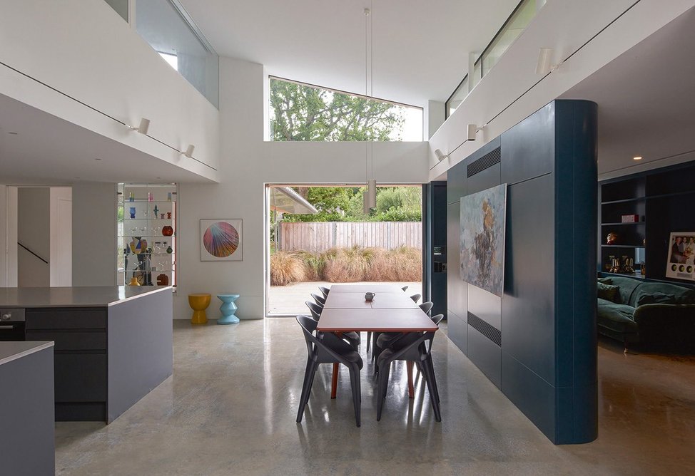 The kitchen/ dining area is separated by a blue wall from the sitting room. Both spaces have double aspect windows onto the courtyard gardens.