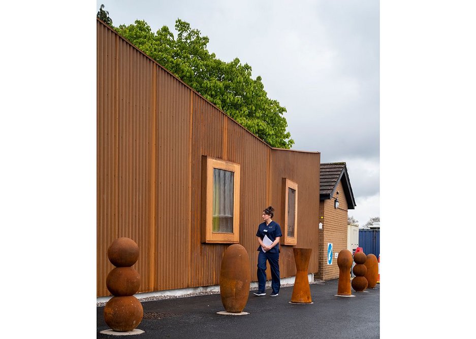 Containers and small buildings clutter the space around the back of Velindre Cancer Centre. The Maggies centre provides a more definite edge