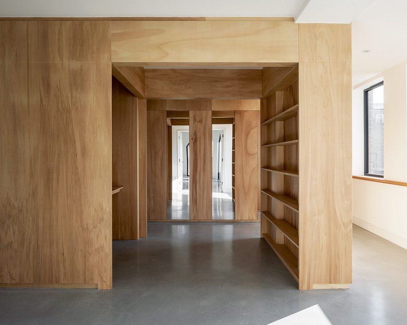 View through timber workspace in the entrance hall, with mirrors beyond reflecting the pointed windows of the living room.