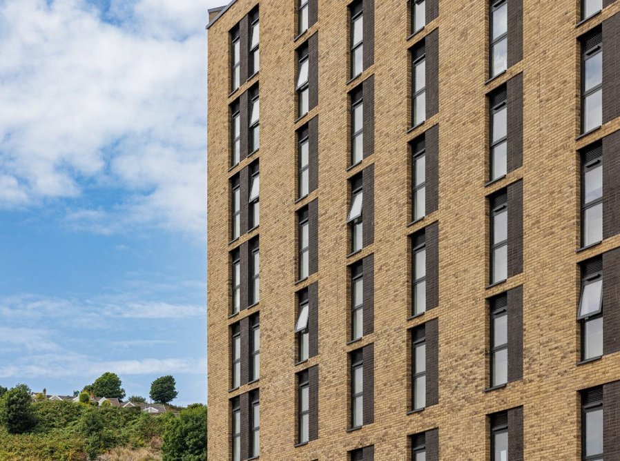 The brick facade of the main building contrasts with the metal clad tower.