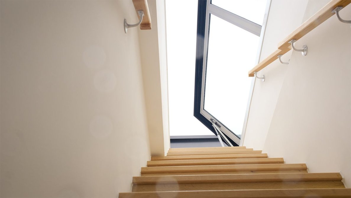 Looking up a staircase to the roof. The rooflights are dual-purpose - skylight and roof access in one.