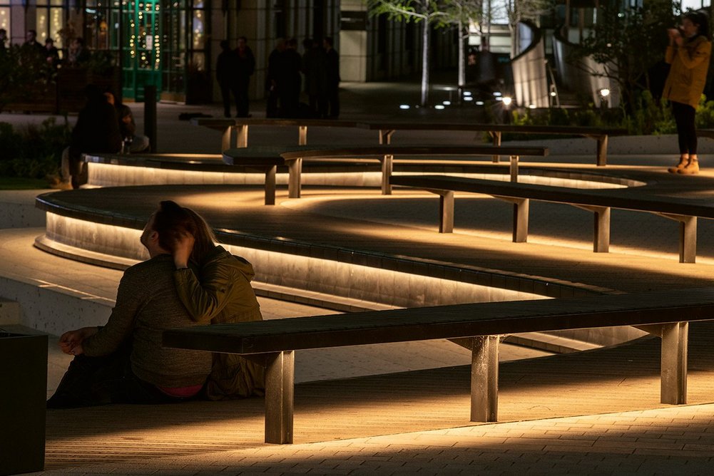 LED lighting is integrated beneath the rim of the ridgeline that meanders through the square and under benches.