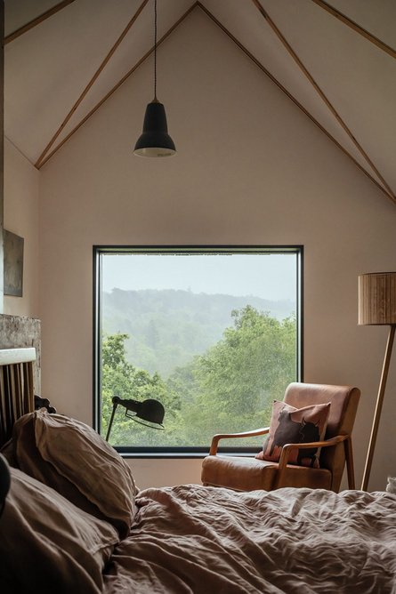 View from the bed head, with timber trusses exposed above with white plaster in between.