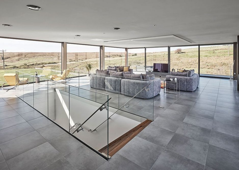 Looking from the kitchen/dining area towards the moors in the glass box, sleekly finished, the manicured grass beyond.