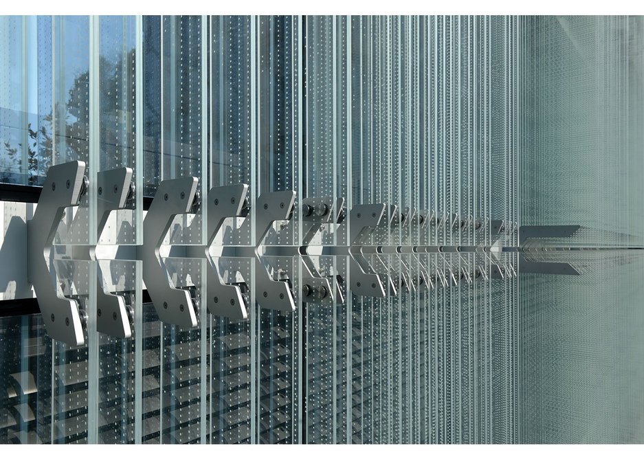 Aluminium clamps fixed at storey height  to the aluminium cladding framework hold the glass blades in place.