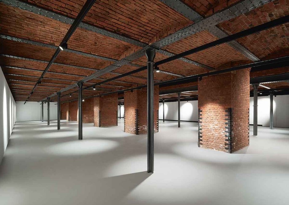 A pigeon grey concrete floor finish benignly offsets the colour and complexity of the flat arched, cast iron structure supporting the museum’s New Warehouse space above.