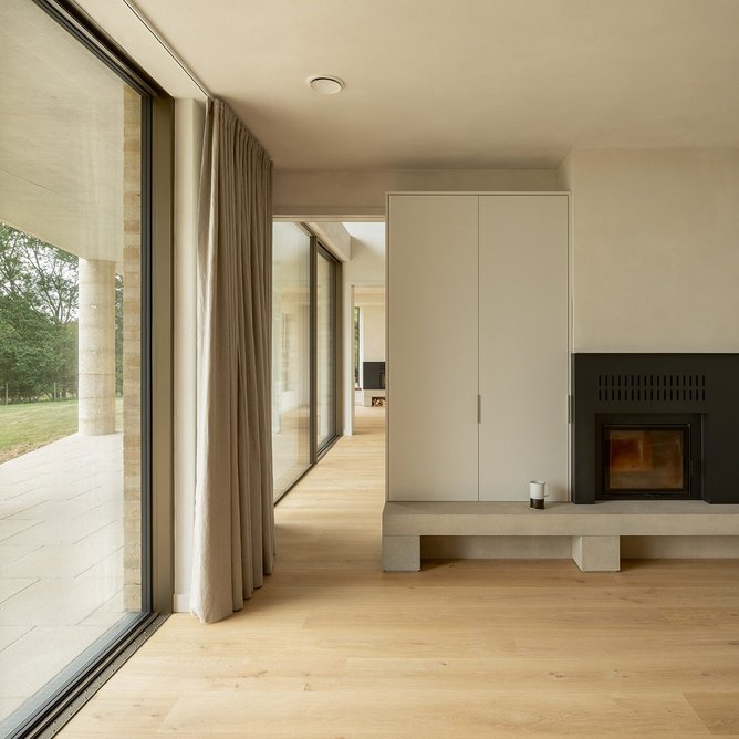 View past the double-sided fireplace from the kitchen/family room into the double-height hall.