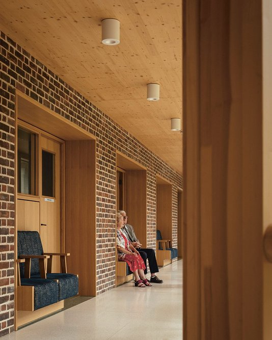 The spine wall near the admin office, shop and wellbeing suite is set with timber seating, allowing residents to look at the garden and watch other residents come and go.