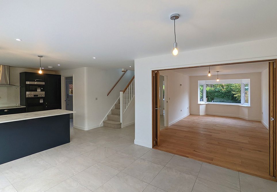 Open-plan kitchen and dining area with oak bifold doors opening into the living room.