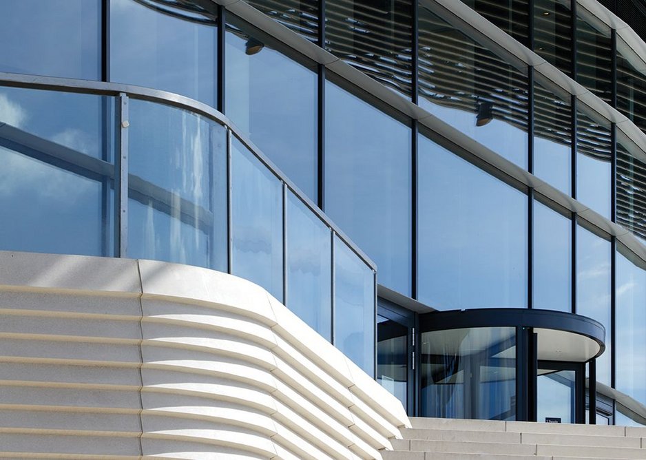The reconstituted stone stair flows into the vertical cladding at ground level.