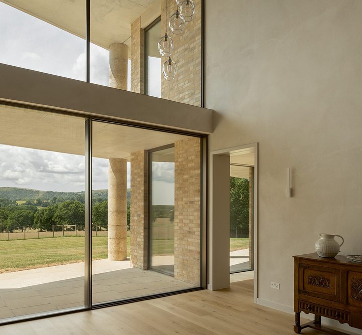 View out onto the South Downs hills from the double-height hall at the centre of the plan. The colonnade steps past at both ground and first floor.