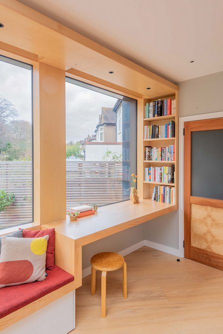 A table overlooking the garden is incorporated into the oak joinery, with storage under the adjacent window seat.