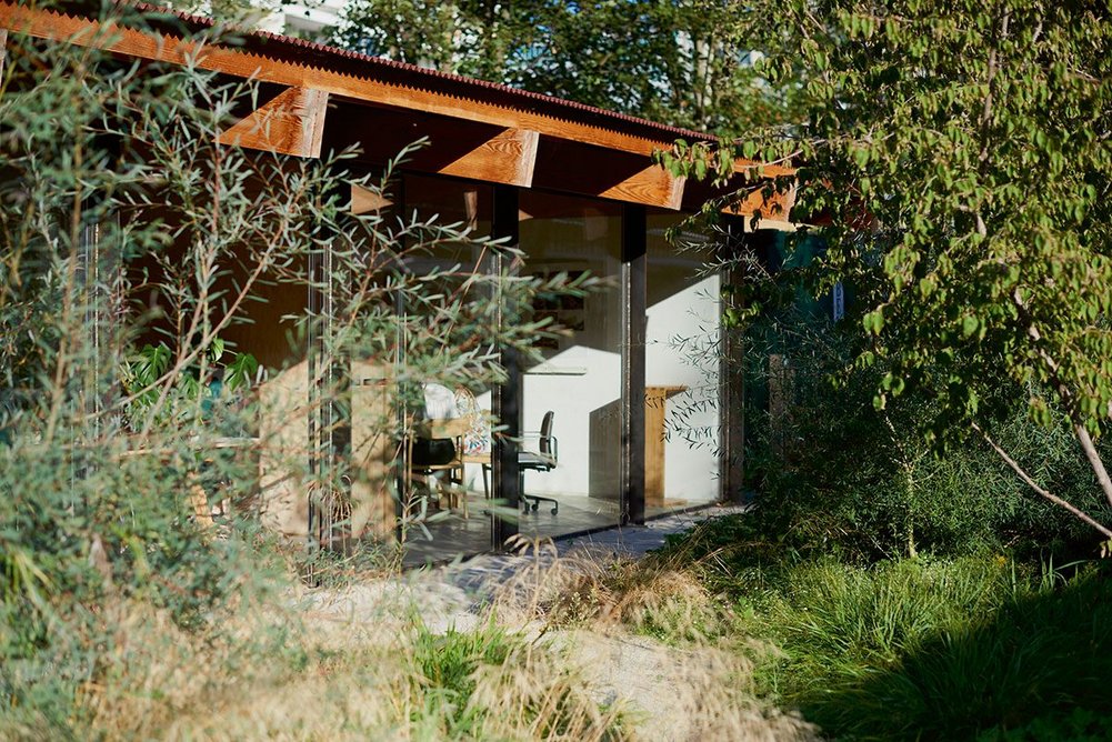 The timber beams of Feilden Fowles’ studio cantilever outdoors to support a covered walkway.