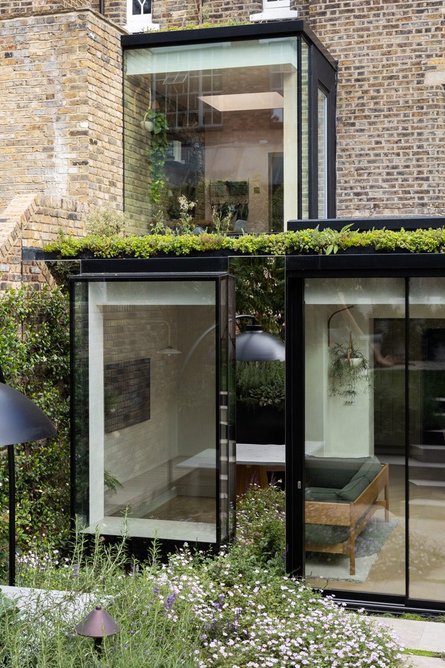 Detailed view of oriel window, planted bed and polished stainless steel panels giving a sense of being enveloped in the garden.