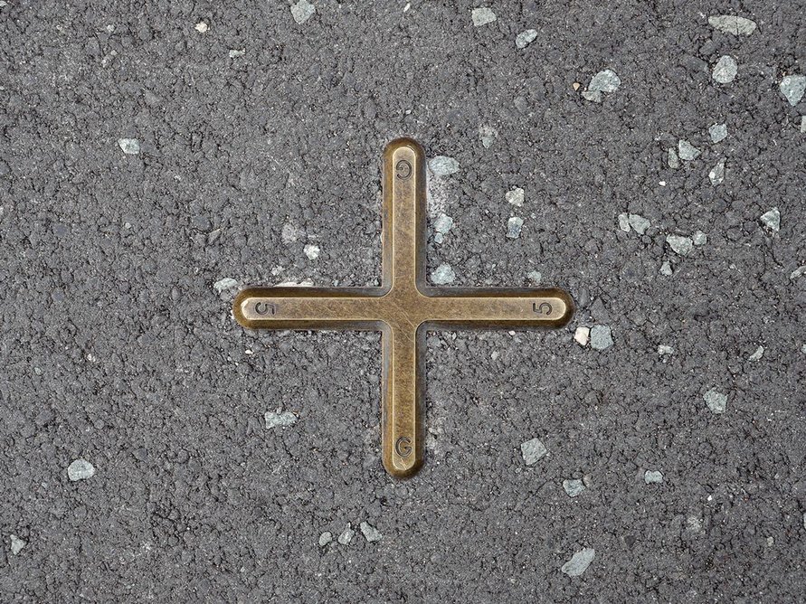 Small brass markers set into the tarmac and paving denote pitch positions.