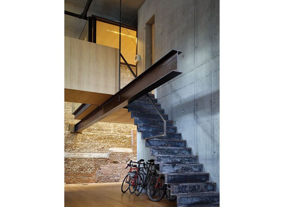 An apparently cantilevering single beam supports the meeting room box, accessed by a folded steel stair.