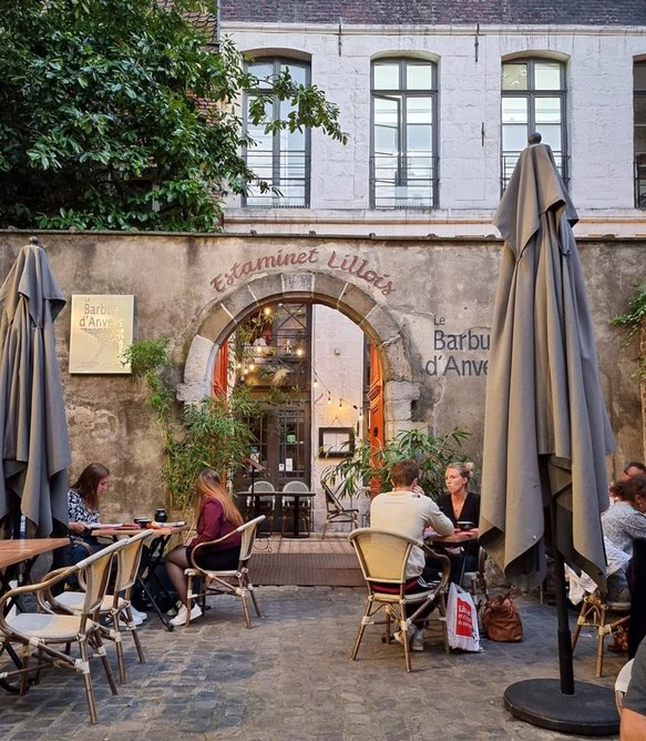 A typical café in Lille with outdoor seating, surrounded by buildings from varying eras, France.