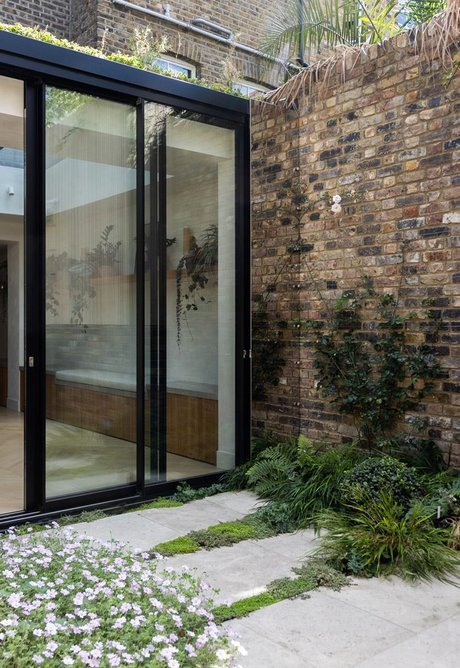 Detailed view of London stock garden wall reflected in stainless steel panels of rear extension.