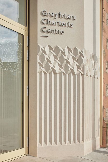 A deeply-grooved and highly tactile cast concrete wall announces the entrance to the new centre.