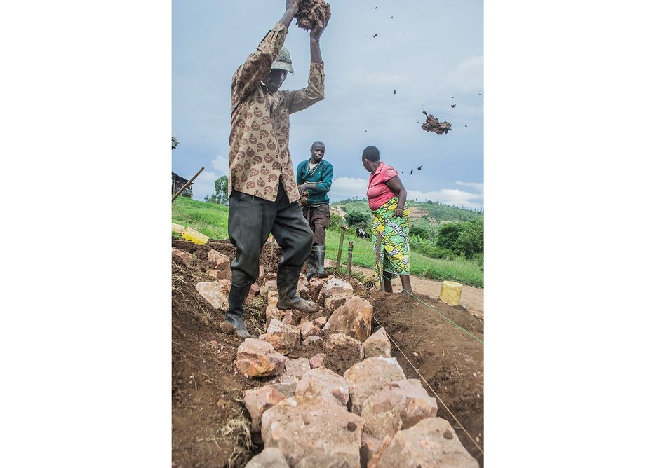 Damacent slams wet mud mortar into the foundation joints, Ntarama, Rwanda, November 2014.