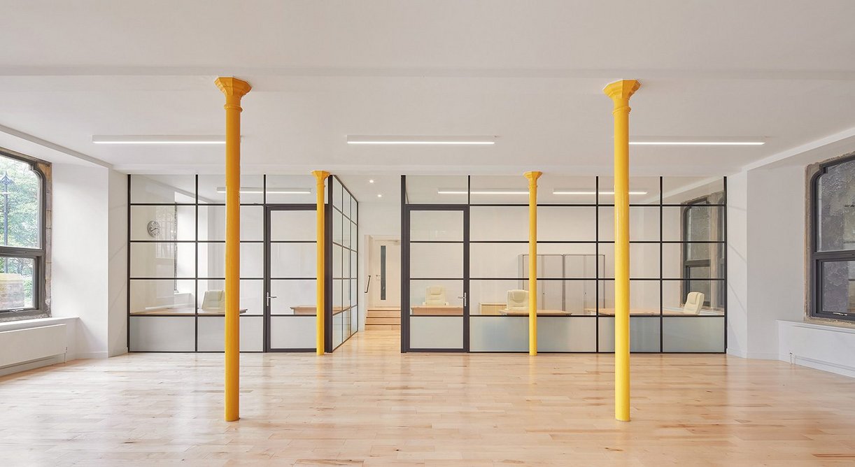 At the lower level, yellow columns support the mezzanine above. Glazed partitions create light and airy work spaces.