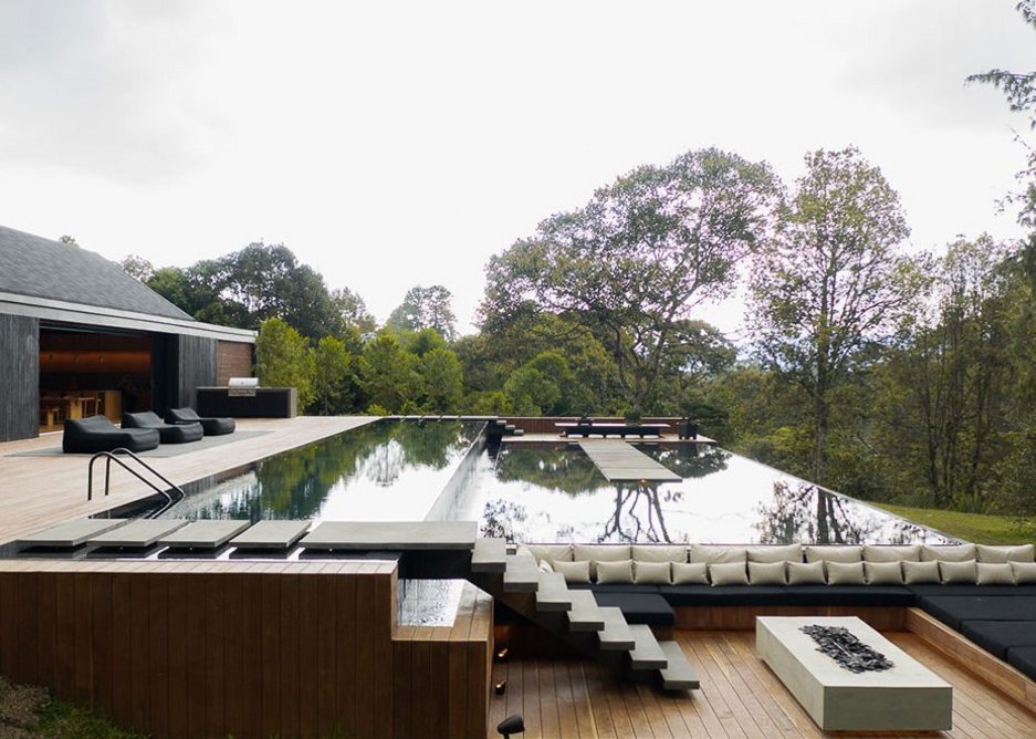 The decking, pool and water mirror with lower level seating area and Neolith Beton fireplace.