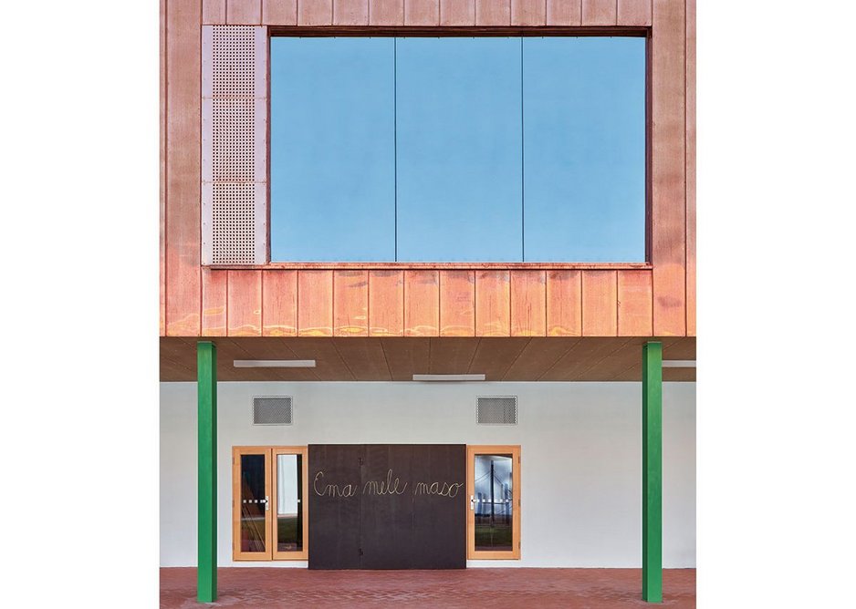 A new copper box of classrooms partially supported by green stilts replaces the roof of one wing to the courtyard.