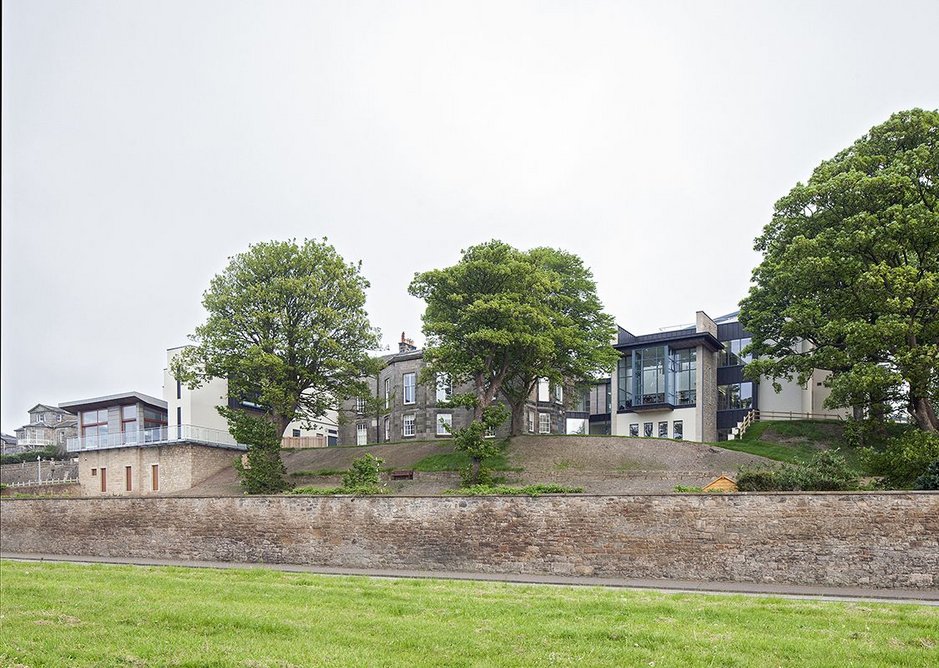 From below the small inland cliff, historic house flanked by two new additions