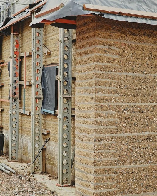 The house under construction. Rammed earth is combined with layers of trass lime mortar to manage erosion.