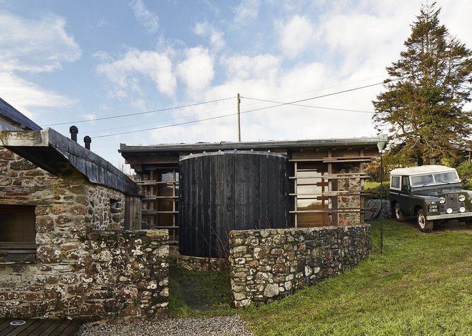 A lead gutter drops water onto a small pile of rocks. The bedroom wing (right) was added to by a drum with bathrooms.