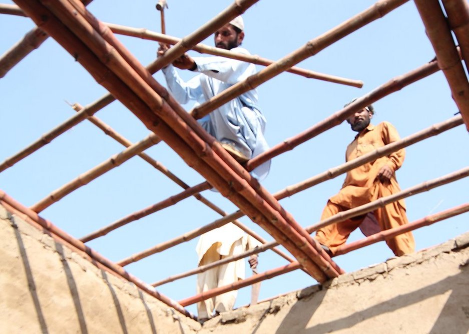 Villagers put a roof on mud hut built to Yasmeen Lari's design.