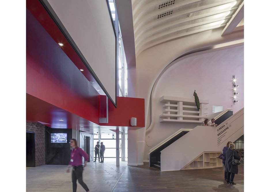Inside the performance foyer the curves of the art deco cinema take centre stage in contrast with the bold, rectilinear red of the stairs and mezzanine. Chester Storyhouse, Bennetts Associates.